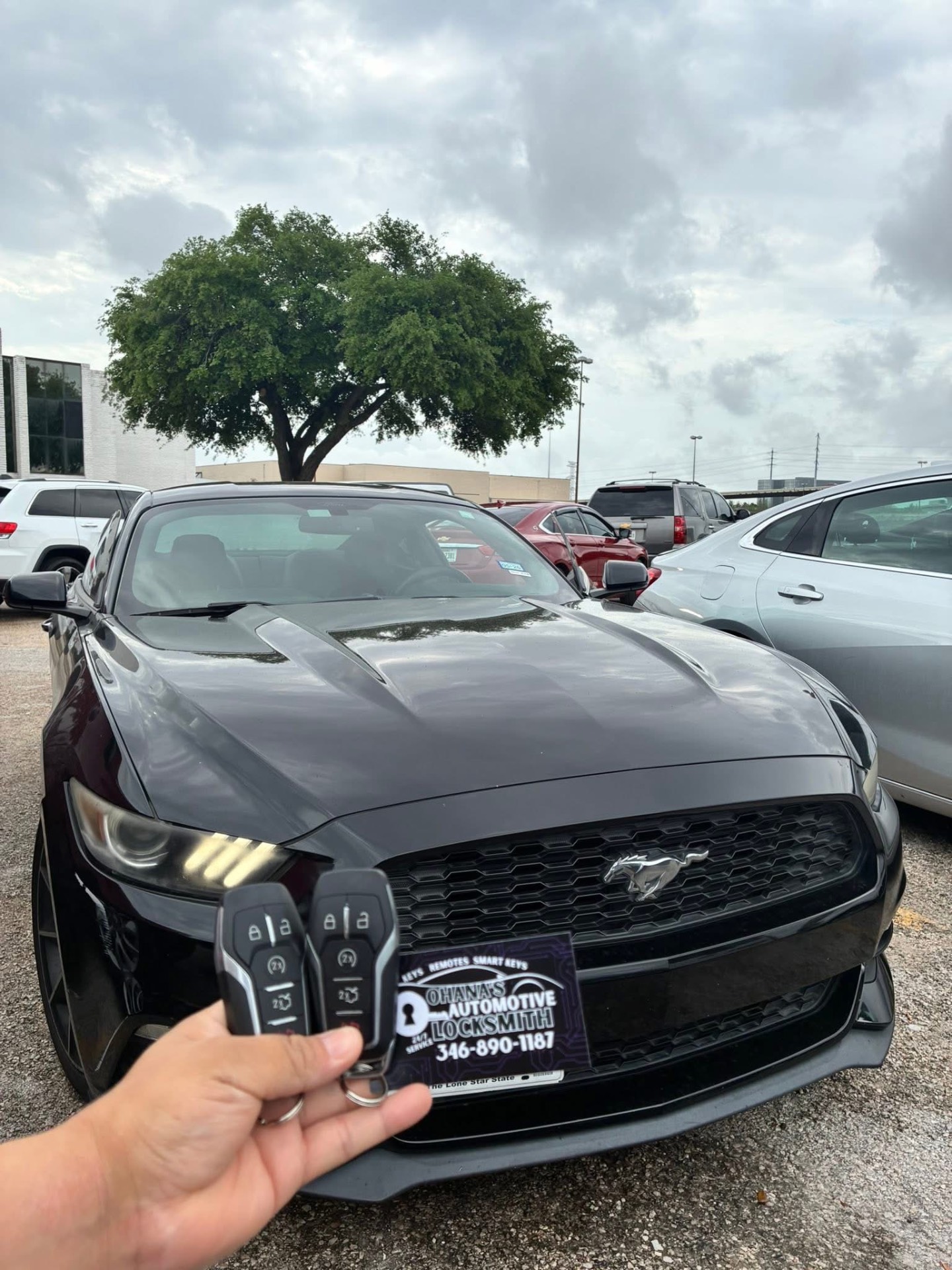 Houston automotive locksmith holding two programmed Ford Mustang smart key fobs in front of the vehicle